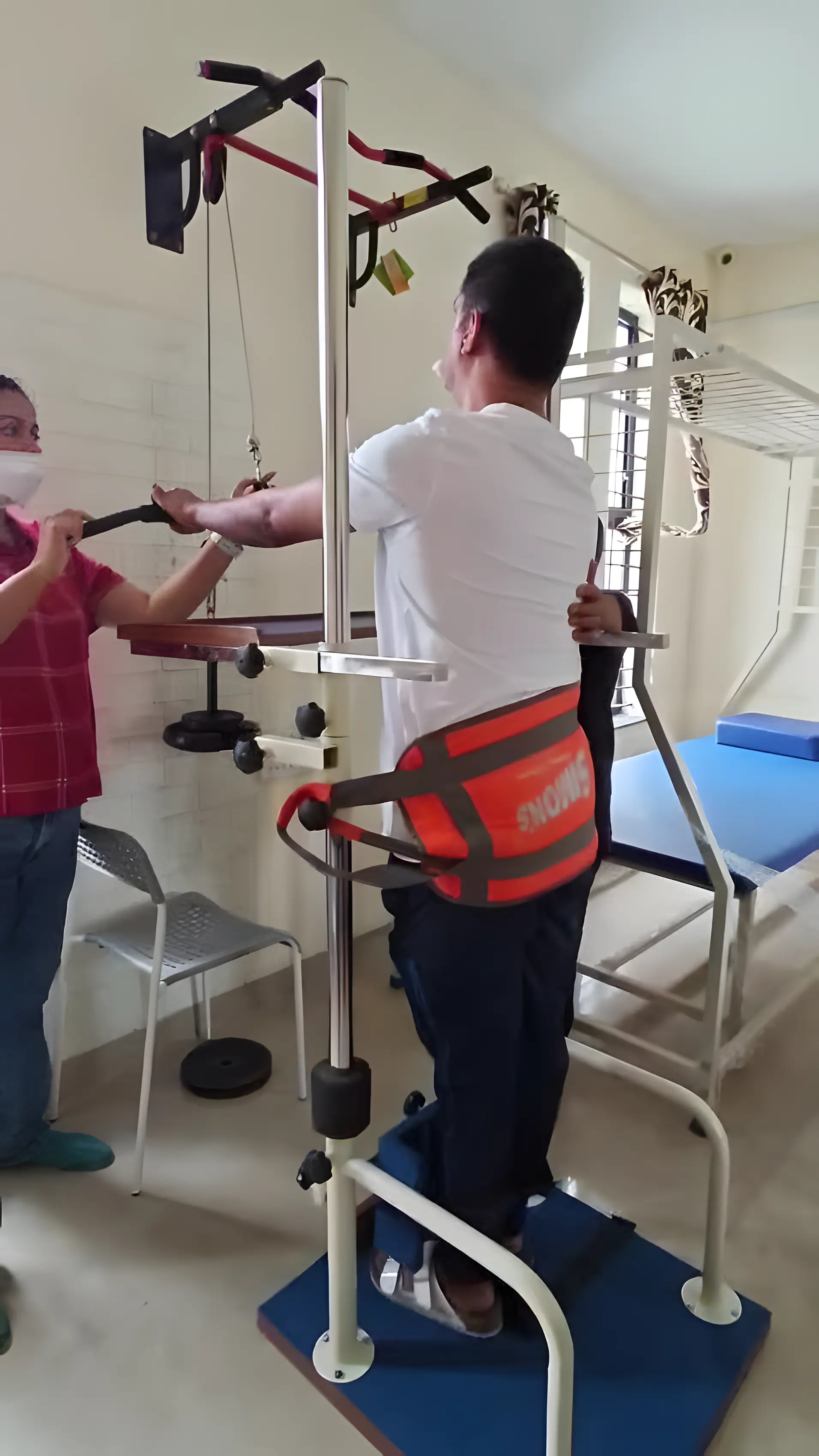 Physiotherapist assisting a Stroke patient with bilateral symmetrical upper limb strengthening using body support and standing frame at Regen Neuro Rehabilitation Physiotherapy Centre