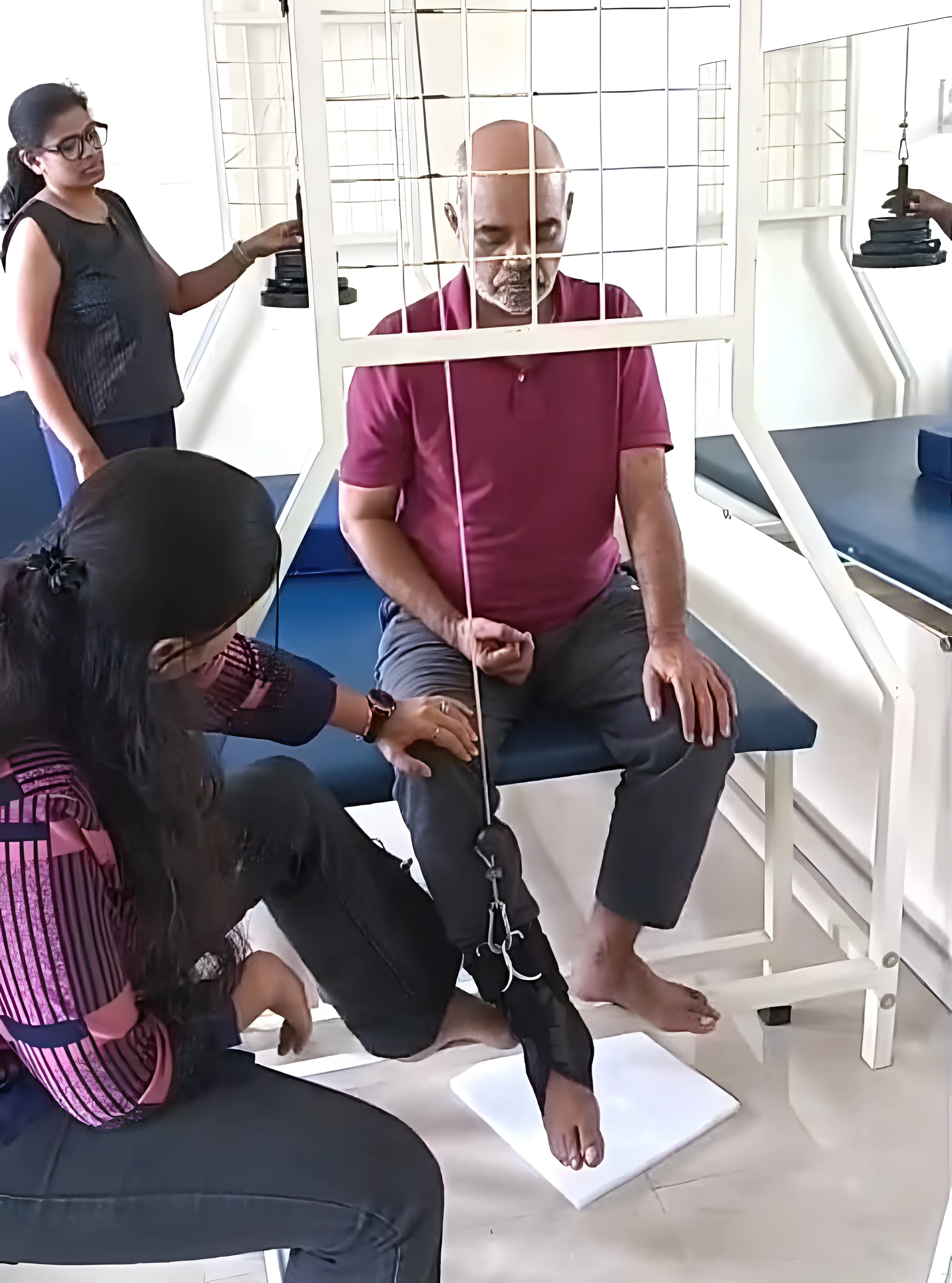 Physiotherapists assisting a patient with Active Knee Flexion activity using suspension at Regen Neuro Rehabilitation Physiotherapy Centre