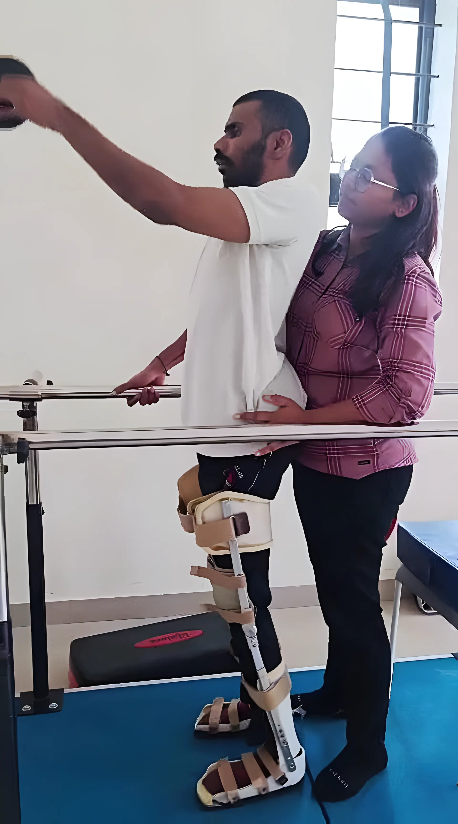 Physiotherapist assisting a patient with trunk balance training on lower limbs using parallel bars at Regen Neuro Rehabilitation Physiotherapy Centre